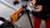 FILE - A worker at a state-owned Pertamina petrol station holds money as a motorcycle is filled with subsidised fuel in Jakarta, Oct. 31, 2014. 