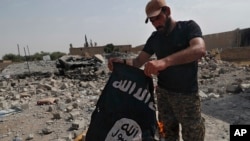 FILE - A fighter of the Christian Syriac militia that battles Islamic State group militants under the banner of the US-backed Syrian Democratic Forces, burns an IS flag on the front line on the western side of Raqqa, July 17, 2017.