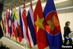 Seorang perempuan melewati bendera KTT ASEAN di Suntec Convention Center di Singapura, 11 November 2018. (Foto: REUTERS/Edgar Su)
