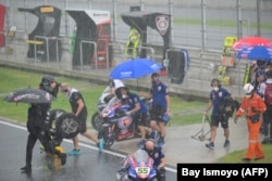 Pembalap dan kru pit meninggalkan gridline karena hujan saat World Superbike Championship di Sirkuit Mandalika. (Foto: AFP/Bay ismoyo)