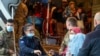 FILE - In this image provided by the US Army, US military personnel, and Kosovo security officials help Afghan refugees after their arrival at the Pristina International Airport in Kosovo on Oct. 16, 2021.