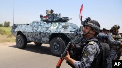 FILE - Iraqi federal policemen are seen patrolling Baghdad's Abu Ghraib suburb June 28, 2014.