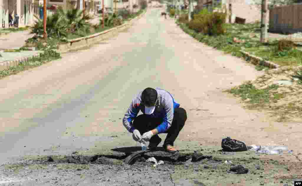 A Syrian man collects samples from the site of a suspected toxic gas attack in Khan Sheikhun, in Syria’s northwestern Idlib province, April 5, 2017.