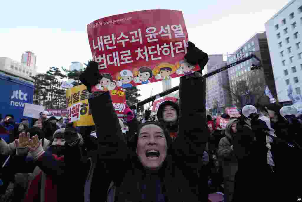 People celebrate after hearing the news that South Korea's parliament voted to impeach President Yoon Suk Yeol outside the National Assembly in Seoul, Dec. 14, 2024. The signs read 'Punish the rebellion leader Yoon Suk Yeol.' Parliament has impeached Yoon over his martial law decree, a move that ended days of political paralysis but set up an intense debate over Yoon’s fate. 
