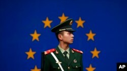 Seorang polisi paramiliter China sedang bertugas di depan bendera Uni Eropa di luar kantor delegasi Uni Eropa untuk China, di Beijing, 28 Oktober 2011. (Foto: AP)