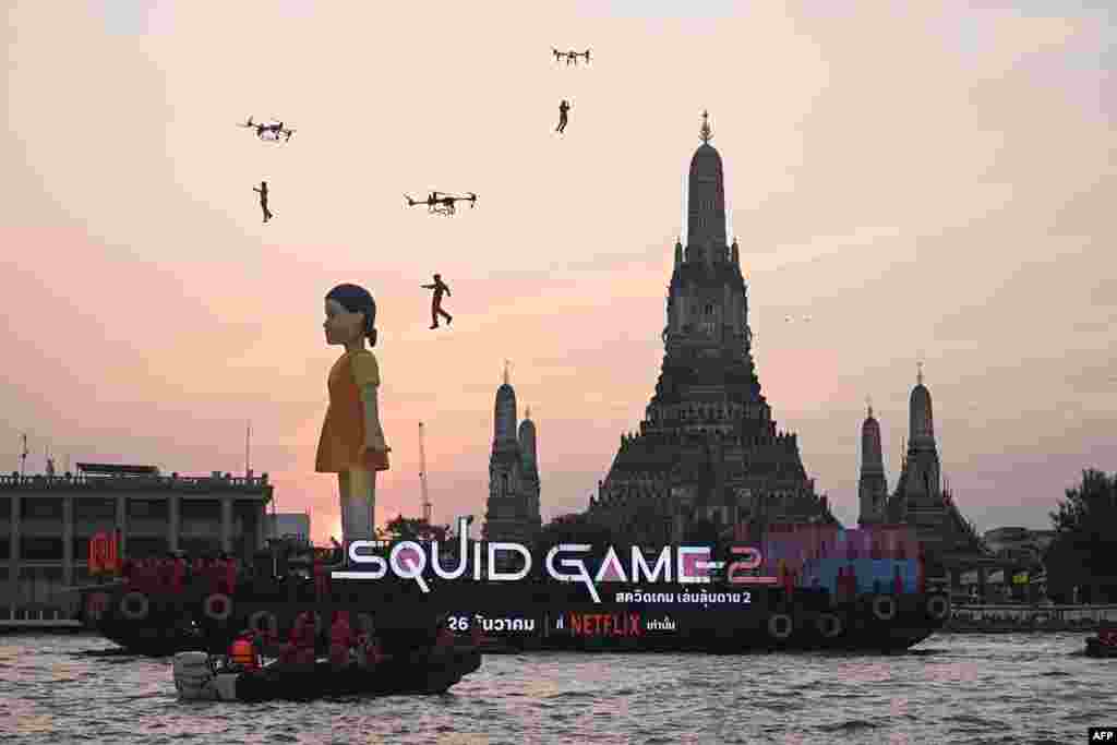 A 12-meter-tall statue of Young-hee, the iconic doll from Netflix's South Korean TV series Squid Game is seen on a barge in front of Wat Arun temple on the Chao Prayer River ahead of the launch of Season 2, in Bangkok, Thailand.