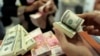 Seorang pegawai valas menghitung uang kertas dollar AS dan rupiah, di Makassar, Sulawesi Selatan, 31 Januari 2013. (Foto: Yusuf Ahmad/Reuters)