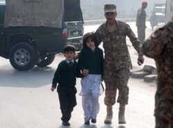 FILE - A soldier escorts schoolchildren from the Army Public School that was attacked by Taliban gunmen in Peshawar, Pakistan, Dec. 16, 2014.