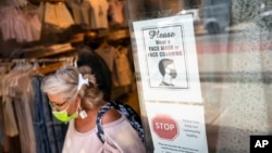Seorang pelanggan yang mengenakan masker keluar dari toko di Broadway di distrik perbelanjaan ritel di lingkungan SoHo di wilayah Manhattan, New York, Jumat, 14 Mei 2021.. (Foto: AP)