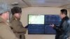 Pemimpin Korea Utara Kim Jong-un (kanan) berbicara dengan pejabat militer selama pengamatan terhadap apa yang dikatakan media pemerintah sebagai uji tembak rudal hipersonik di sebuah lokasi yang dirahasiakan di Korea Utara (12/1). (KCNA via KNS/AFP)
