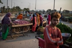 FILE - Vendors and customers are seen without masks at a market on the outskirts of New Delhi, India, Nov. 20, 2020.