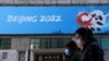 Orang-orang berjalan melewati spanduk Olimpiade Musim Dingin Beijing 2022 di Beijing, 27 Oktober 2021. (Foto: Reuters)