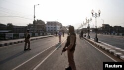 Indian security personnel stand guard on a deserted road during restrictions in Srinagar, Aug. 5, 2019. 