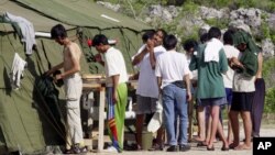 FILE - Men shave, brush their teeth and prepare for the day at a refugee camp on the Island of Nauru, Sept. 21, 2001.