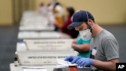 Workers prepare mail-in ballots for counting, Wednesday, Nov. 4, 2020, at the convention center in Lancaster, Pa., following Tuesday's election. (AP Photo/Julio Cortez)
