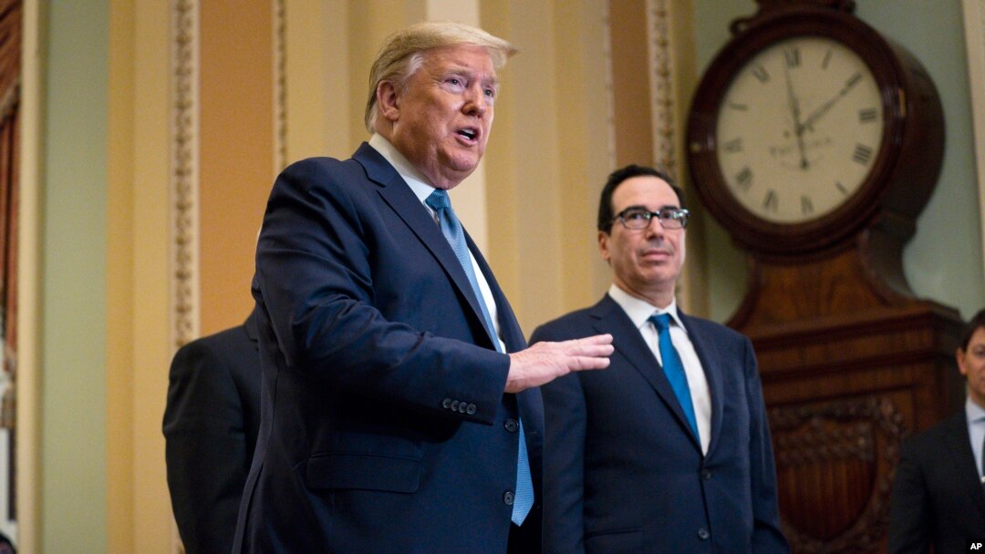 Treasury Secretary Steven Mnuchin listens as President Donald Trump talks to reporters after meeting with Republican lawmakers on Capitol Hill, March 10, 2020, in Washington. 