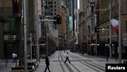 People in protective face masks walk through the quiet city center during a lockdown to curb the spread of COVID-19 outbreak in Sydney, Australia, July 28, 2021.