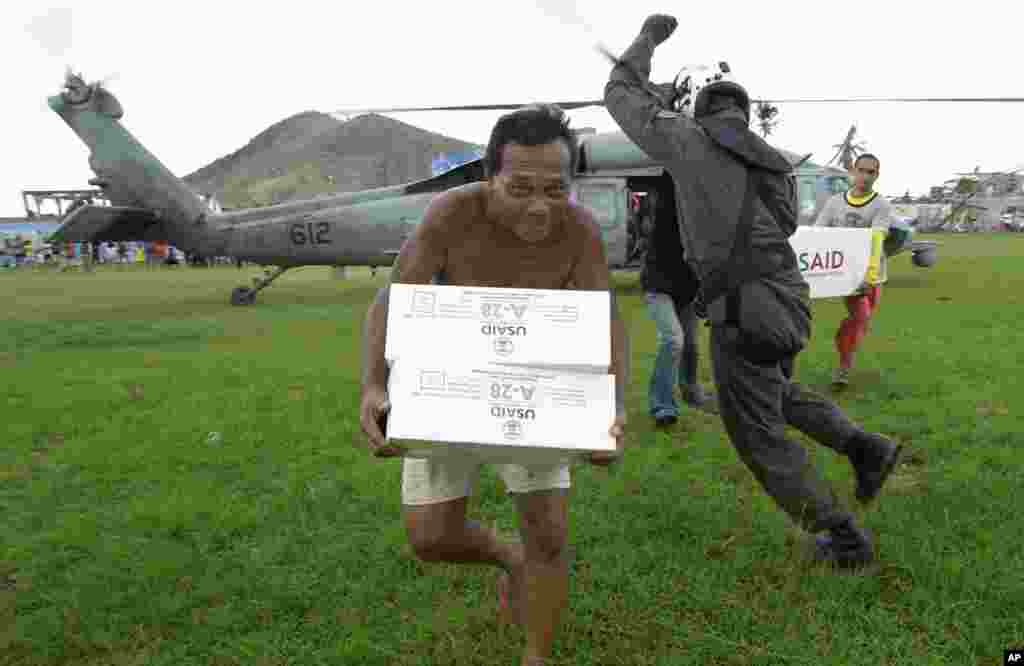 A Philippine man carries aid from a U.S. Navy Seahawk helicopter in Palo, Philippines, Nov. 20, 2013.