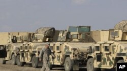 一名美軍士兵於11月7日在伊拉克巴格達勝利營軍事裝甲車前走過，準備將裝甲車運出伊拉克。(資料圖片)
