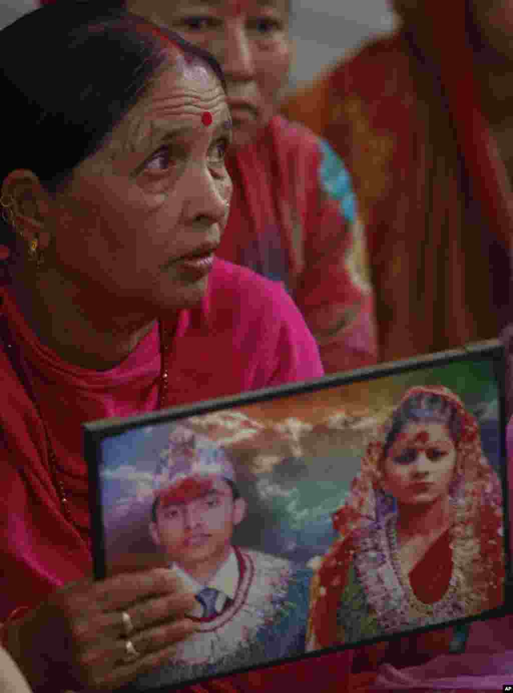 Indian woman Padma holds a photograph showing her son Bharat and daughter in law Partima with whom she has not been able to establish contact after Saturday's earthquake in Nepal, during a prayer ceremony for the earthquake affected at a Hindu temple in Jammu, India.