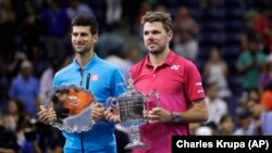 Novak Đoković i Sten Vavrinka sa trofejima namenjenim pobedniku i poraženom u finalu