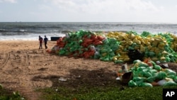 Ludi hodaju pored hrpa plastike koju je okean izbacio na obalu nakon požara na kontejnerskom teretnjaku MV Eks-pres perl u Kapungodi, u predgrađu Kolumba, Šri Lanka, 11. juna 2021.