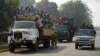 A national police car passes by Muslim Centrafricans riding aboard trucks on their way to their villages in Bangui, three days before elections for the next interim President of Centrafrica, Jan. 17, 2014.