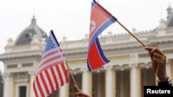 Residents hold US and North Korean flags while they wait for motorcade of North Korea's leader Kim Jong Un en route to the Metropole Hotel for the second US- North Korea summit in Hanoi, Vietnam February 28, 2019. REUTERS/Kham
