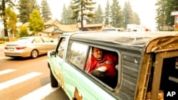 Seorang warga Tahoe terbaring di atas truk pick-up saat melakukan evakuasi ketika kebakaran Caldor mendekati South Lake Tahoe, California, 30 Agustus 2021. (Foto: AP)