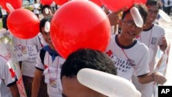 Pemuda memegang balon berbentuk kondom dalam peringatan Hari AIDS Sedunia. (foto: AP)