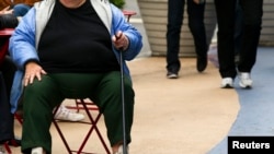 FILE - An overweight woman sits on a chair in Times Square in New York, May 8, 2012. 