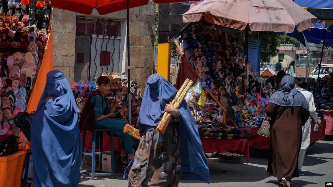 Burqa-clad Afghan women shop at a market area in Kabul on August 23, 2021, following the Taliban's military takeover of the country.