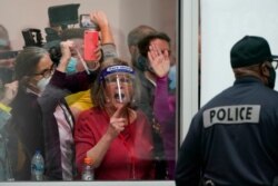 FILE - Election challengers yell as they look through the windows of the central counting board as police were helping to keep additional challengers from entering due to overcrowding, in Detroit, Nov. 4, 2020.