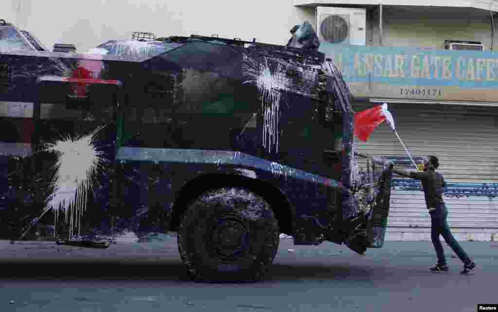 Seorang demonstran menghalangi kendaraan polisi anti huru-hara dengan membawa bendera Bahrain untuk menghalangi masuk ke desa Bilad Al Qadeem, selatan ibukota Manama, kediaman ulama Syiah tokoh oposisi, Sheikh Ali Salman. 