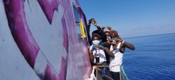 In this undated handout photo, people pose after being rescued by the Louise Michel, a migrant search-and-rescue ship operating in the Mediterranean and financed by British street artist Banksy, at sea. (MV Louise Michel/Handout via Reuters)