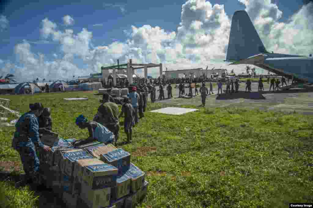 U.S. military personnel and and Philippine civilians unload relief supplies. (U.S. Navy)