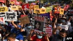Protesters hold up signs during a demonstration outside the Myanmar Central Bank against the military coup in Yangon on February 16, 2021. (Photo by YE AUNG THU / AFP)