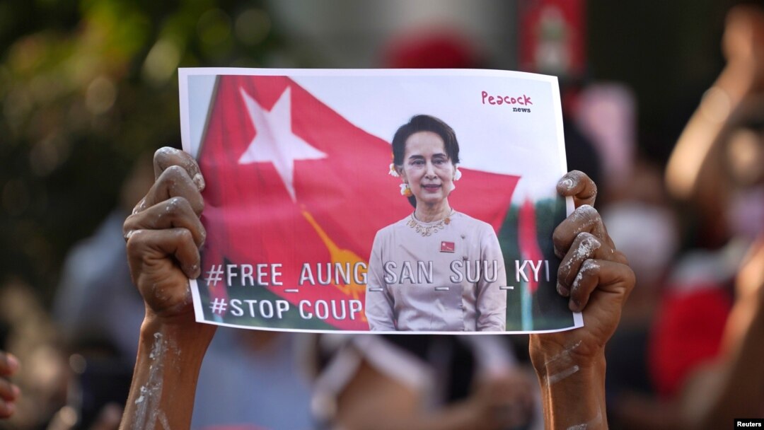 နိုင်ငံတော်အတိုင်ပင်ခံ ပုဂ္ဂိုလ် ဒေါ်အောင်ဆန်းစုကြည်ရဲ့ ဓာတ်ပုံ ပို့စ်စတာကို ကိုင်ပြီး ဆန္ဒပြနေသူတဦးကို ထိုင်းနိုင်ငံ ဘန်ကောက်မြို့ရှိ မြန်မာသံရုံးရှေ့မှာတွေ့ရ။ (ဖေဖော်ဝါရီ ၀၁၊ ၂၀၂၁)