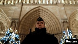Francuski žandarm na straži. Jake policijske snage obezbeđuju prilaze katedrali Noterdam tokom proslave Božića u Parizu (REUTERS/Christian Hartmann - RTX2WDZR)