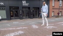 Seorang pria mengambil foto “cuitan-cuitan kebencian,” sebagai bagian dari proyek seni “#HEYTWITTER” yang dibuat oleh Shahak Shapira, di pelataran kantor Twitter di Hamburg, Jerman (YouTube via REUTERS) Germany Aug. 4, 2017 in this picture obtained from social media.