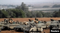 Israeli soldiers stand atop armored personnel carriers in a staging area near the border with Gaza, in southern Israel, Nov. 13, 2019. 