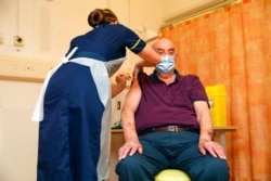 Brian Pinker, 82, receives the Oxford University/AstraZeneca COVID-19 vaccine from nurse Sam Foster at the Churchill Hospital in Oxford, England, Jan. 4, 2021.