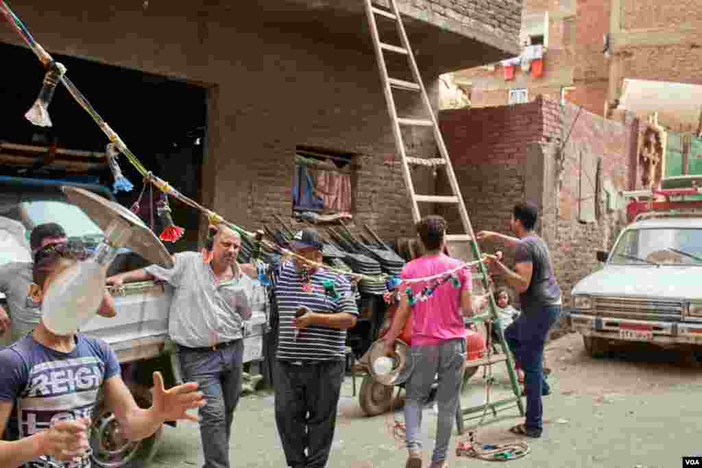Getting ready for a street wedding, a worker in a Cairo neighborhood hangs a string of lights that is hooked up to overhead power lines. (H. Elrasam/VOA)