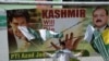 FILE - A Pakistani Kashmiri youth holds Pakistani and Kashmiri flags as he walks past a banner featuring a photograph of Pakistan's Prime Minister Imran Khan, left, during a rally in Muzaffarabad, Sept. 13, 2019. 