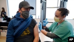 Brian Kennedy (kiri), seorang guru olahraga di SD Green Valley, menerima suntikan vaksin COVID-19 dalam vaksinasi massal untuk karyawan sekolah negeri di Denver, Colorado, Februari 2021.