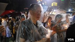 參加六四燭光晚會的人士身穿雨衣，並小心保護手中的燭光免被雨水淋息