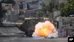Sebuah bom yang dilemparkan oleh warga Palestina meledak di samping kendaraan tentara Israel selama serangan militer di kamp pengungsi Jenin, kubu militan, di Tepi Barati, Selasa, 4 Juli 2023. (AP/Majdi Mohammed)