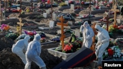 Petugas mengenakan alat pelindung diri (APD) menguburkan seseorang di kuburan khusus korban virus COVID-19 di pinggiran Saint Petersburg, Rusia, 6 November 2020.