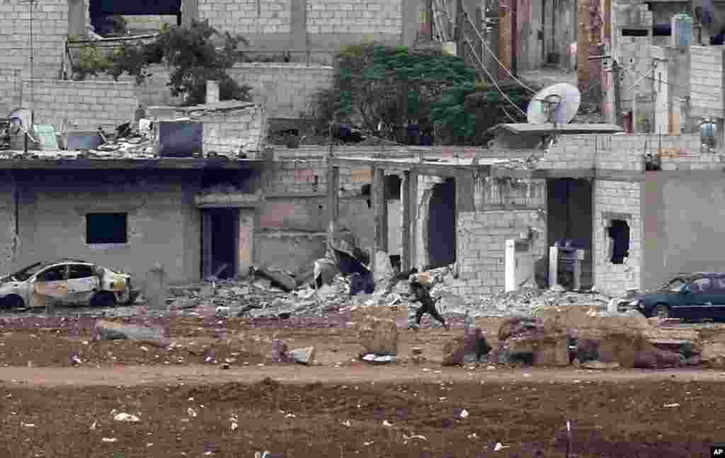 A Kurdish fighter runs to her position in Kobani, Syria, during fighting between Syrian Kurds and the militants of Islamic State group, Oct. 16, 2014.