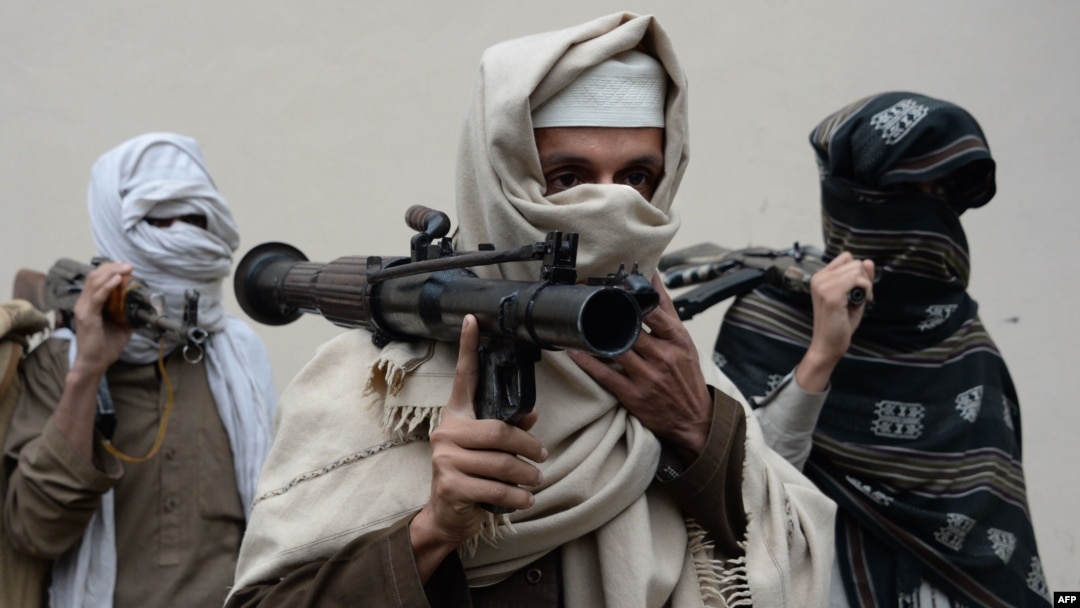 FILE - Former Afghan Taliban fighters carry their weapons before handing them over as part of a government peace and reconciliation process at a ceremony in Jalalabad, Jan. 12, 2016. 